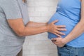 An elderly woman touches the belly of her pregnant daughter. Close-up.