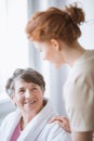 Elderly in bathrobe and young volunteer at nursing home