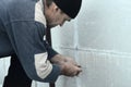 An elderly worker creates holes in the expanded polystyrene wall for the subsequent drilling and installation of an umbrella dowel