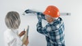 An elderly worker in a hard hat and a gray-haired female engineer with a tablet in their hands are discussing plans Royalty Free Stock Photo