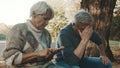 Elderly worried couple sitting on the bench in despair. Woman counting last coins