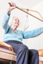 Elderly 96 years old woman exercising with a stick sitting on her bad.