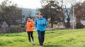 Elderly and young smiling women in sports clothes, running in the park. Grandmother and granddaughter run together