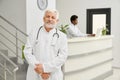 Eldery doctor in coat posing in hospital.