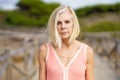 Eldery female walking along a wooden path near the beach., wearing a nice orange dress. Royalty Free Stock Photo