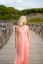 Eldery female walking along a wooden path near the beach., wearing a nice orange dress. Royalty Free Stock Photo