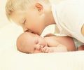 Eldest brother kissing youngest baby, two children lying togethe Royalty Free Stock Photo