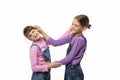 The eldest girl drags the younger one by the ear, isolated