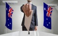 Election or referendum in Australia. Voter holds envelope in hand above ballot. Australian flags in background