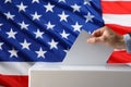 Election in USA. Man putting his vote into ballot box and American flag on background, closeup Royalty Free Stock Photo