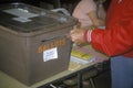 Election volunteer depositing ballots in a ballot box in a polling place, CA Royalty Free Stock Photo