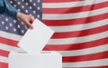 Elections, America. A human hand throws a ballot into the ballot box. American flag on the background. Election concept Royalty Free Stock Photo