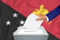 Elections in the country - voting at the ballot box. A man`s hand puts his vote into the ballot box. Flag Papua New Guinea on