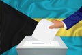 Elections in the country - voting at the ballot box. A man`s hand puts his vote into the ballot box. Flag Bahamas on background Royalty Free Stock Photo