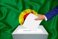 Elections in the country - voting at the ballot box. A man`s hand puts his vote into the ballot box. Flag Zaire on background