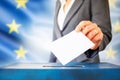 elections in European Union. The hand of woman putting her vote in the ballot box. EU flag in the background Royalty Free Stock Photo