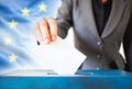 elections in European Union. The hand of woman putting her vote in the ballot box. EU flag in the background Royalty Free Stock Photo