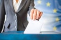 elections in European Union. The hand of woman putting her vote in the ballot box. EU flag in the background Royalty Free Stock Photo