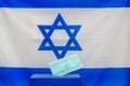 Israeli Elections. Medical face mask in a box for ballot in election on Israel flag background.