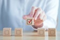 Hand holding check mark on wooden block and blank check box on wooden cubes. Elections and Voting, Vote concept.