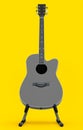 Electric acoustic guitar on stand isolated on yellow background. Royalty Free Stock Photo