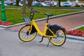 An electric Bicycle stands on a city street. Yellow electric bike in the city