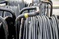 Electric black cables are twisted and stacked in a coil. Cords and wires, electrical and audio equipment, selective focus, tinting