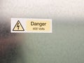 an electric bolt in triangle white yellow and black safety caution sign warning saying danger 400 volts attached to a metal wall Royalty Free Stock Photo