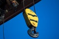 Electric cable hoist with black hook in yellow casing.