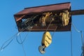 Electric cable hoist with black hook in yellow casing.