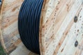 An electric cable in a polymer winding on a wooden coil. A high-voltage cable located on a construction site. Close-up of the Royalty Free Stock Photo