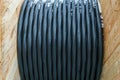 An electric cable in a polymer winding on a wooden coil. A high-voltage cable located on a construction site. Close-up of the Royalty Free Stock Photo