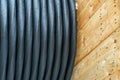 An electric cable in a polymer winding on a wooden coil. A high-voltage cable located on a construction site. Close-up of the Royalty Free Stock Photo