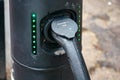 Electric car cable plugged into street charging station connector, green lights on, closeup detail Royalty Free Stock Photo