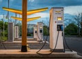 Electric car charging ports illuminated by bright yellow lights in a gas station parking area.