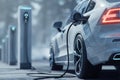 Electric car charging at station in winter landscape Royalty Free Stock Photo