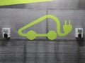 Electric car charging symbol in a parking lot with two sockets.