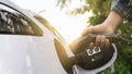 Electric car or ev is charging at station . man use the white power cable and plug on nature background Royalty Free Stock Photo