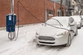 Electric car getting charged in Montreal during snowstorm Royalty Free Stock Photo