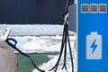 Electric cars charging concept. Car is charged on electric charging station in parking in winter. Blue symbol on electric charging Royalty Free Stock Photo