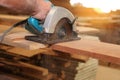 Electric circular saw is being cut a piece of wood by carpenter in carpentry workshop.