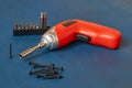 Electric cordless screwdriver with a set of bits, self-cutting screws, close-up on a blue background Royalty Free Stock Photo