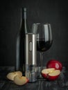 The electric corkscrew stands on a dark wood background. Nearby are red apples, a bottle and a glass of wine. Dark background Royalty Free Stock Photo