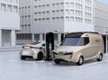 Electric delivery minivan and silver sedan charging at charging station