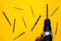 Electric drill and drill bits on a yellow background. Hammer drill or screwdriver flat lay. Top view of professional instrument Royalty Free Stock Photo