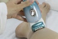 Electric epilator pulls out the hairs in close-up. Slow motion. Woman epilate legs with electric epilator. Girl performs epilation