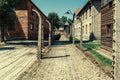 Electric fence with barbed wire and brick prison buildings at the Auschwitz-Birkenau concentration camp Royalty Free Stock Photo