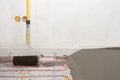 Electric floor heating system installation in new house. Closeup of the rooler for align concrete. Royalty Free Stock Photo