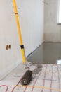 Electric floor heating system installation in new house. Closeup of the rooler for align concrete. Royalty Free Stock Photo