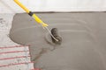 Electric floor heating system installation in new house. Worker align cement with roller. Royalty Free Stock Photo